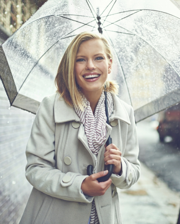 Woman in raincoat smiling with umbrella