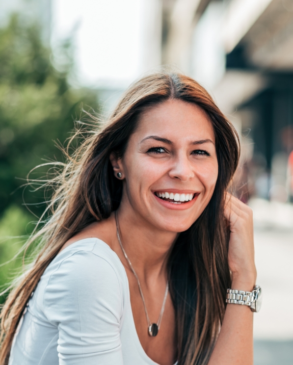 Woman with long brown hair smiling outdoors