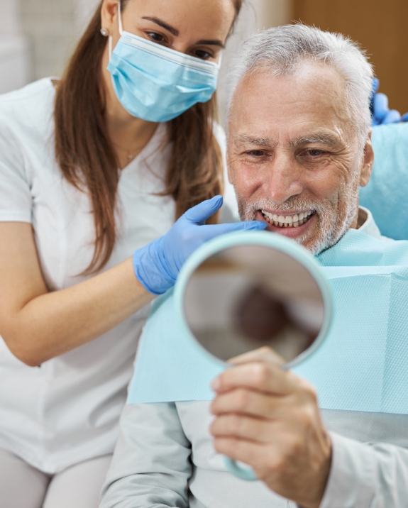 Senior dental patient looking at his smile in a mirror