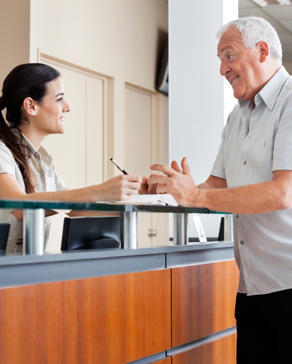 Senior man talking to dental office receptionist