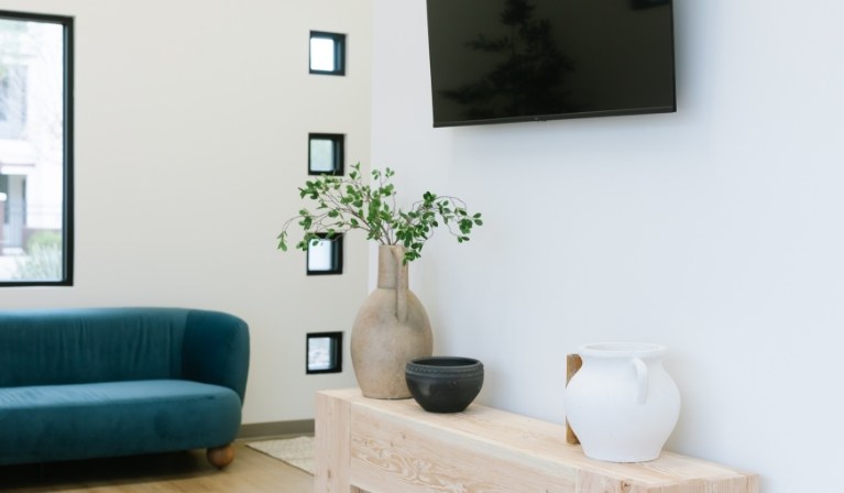 Table with vases and T V screen on wall