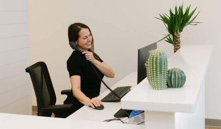 Dental office receptionist smiling while answering phone