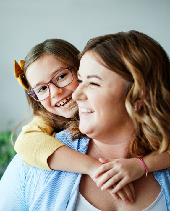 Young girl with glasses hugging her mother