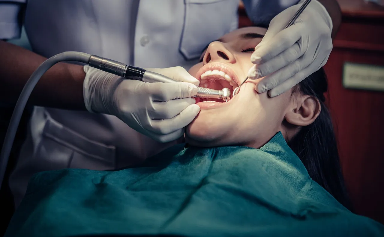 Dentist performing a dental procedure on a patient; dental chair.