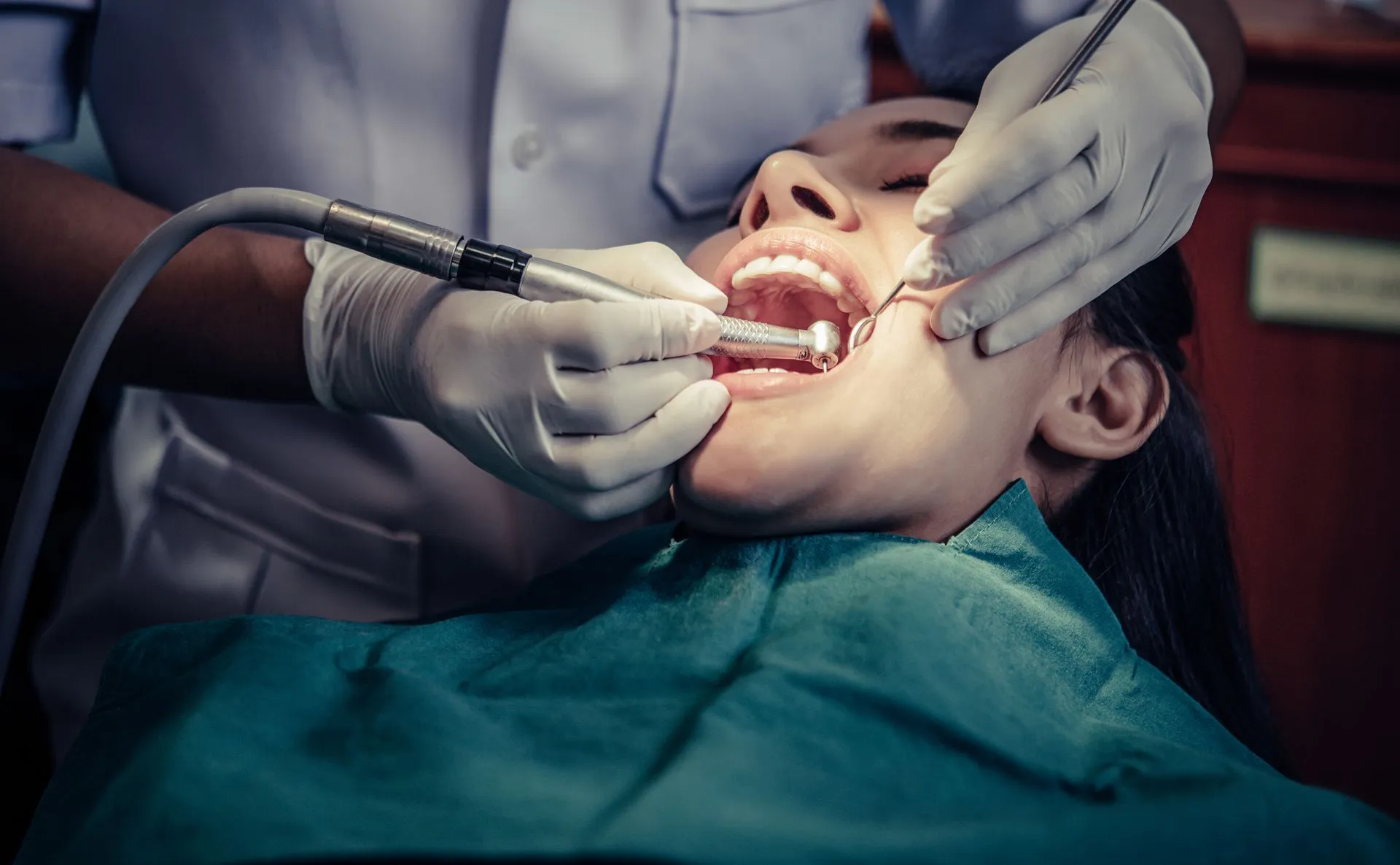 Dentist performing a dental procedure on a patient; dental chair.